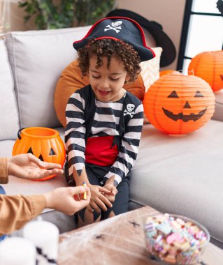 Adorable hispanic boy having halloween party drawing on hand at home