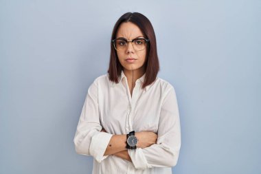 Young hispanic woman standing over white background skeptic and nervous, disapproving expression on face with crossed arms. negative person. 