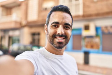 Genç İspanyol adam gülümsüyor. Kendine güveniyor. Kameranın önünde özçekim yapıyor.