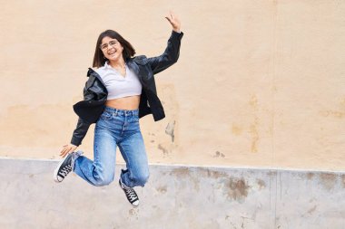 Young beautiful hispanic woman smiling confident jumping at street