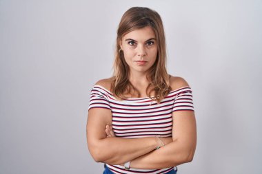 Young hispanic woman standing over isolated background skeptic and nervous, disapproving expression on face with crossed arms. negative person. 