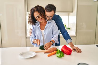 Orta yaşlı İspanyol çift mutfakta yemek pişirirken birbirlerine sarılıyorlar.