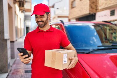 Genç İspanyol kurye sokakta akıllı telefon paketi kullanıyor.