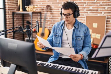 Müzik stüdyosunda müzik notaları tutan genç bir müzisyen.