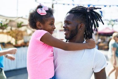 Father and daughter smiling confident hugging each other at street market