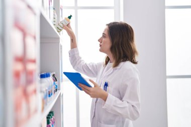 Young woman pharmacist using touchpad organize shelving at pharmacy
