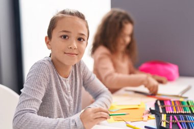 Two kids students sitting on table drawing on notebook paper at classroom