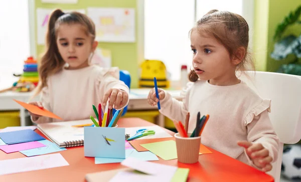 Two kids preschool students sitting on table drawing on paper at kindergarten