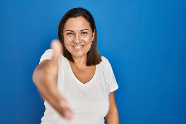 Hispanic Mature Woman Standing Blue Background Smiling Friendly Offering Handshake — Photo