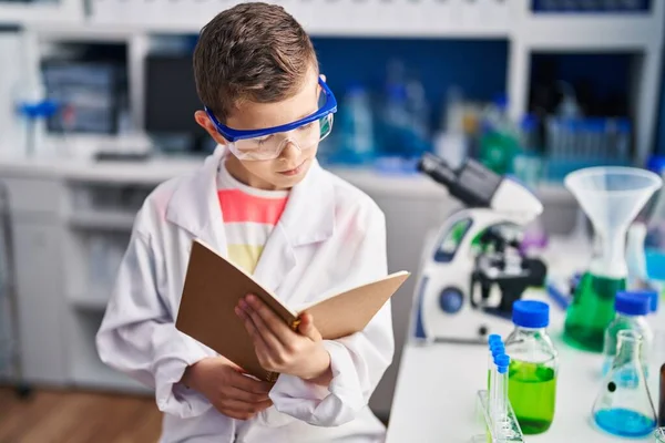 实验室里穿着科学家制服的金发孩子看书 — 图库照片