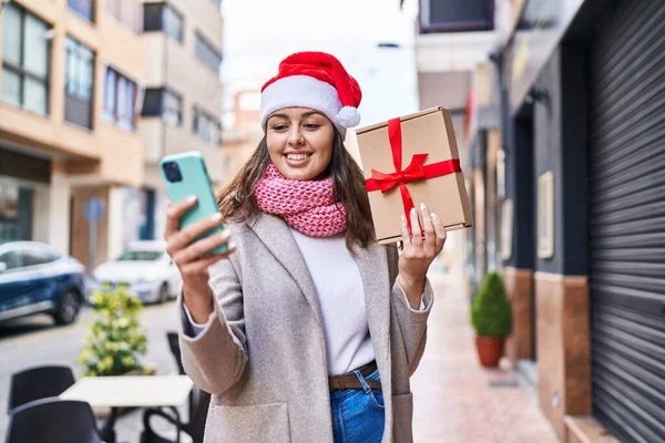 Young Beautiful Hispanic Woman Wearing Christmas Hat Holding Gift Using — Stockfoto