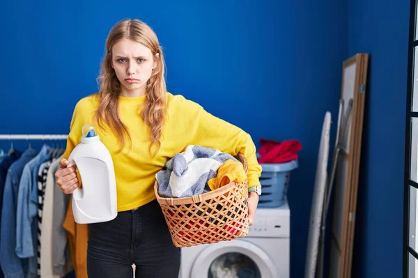 Young caucasian woman holding laundry basket and detergent bottle depressed and worry for distress, crying angry and afraid. sad expression. 