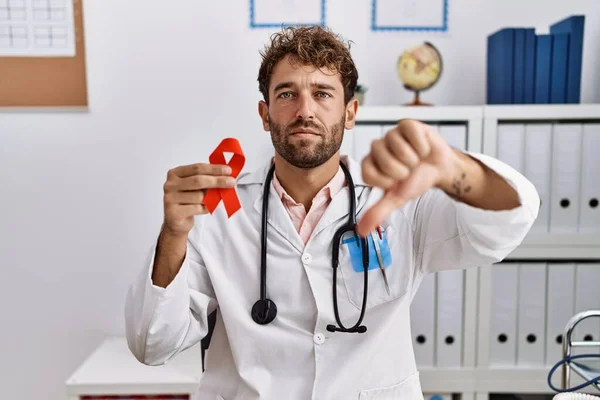 Young Hispanic Doctor Man Holding Support Red Ribbon Medical Clinic —  Fotos de Stock