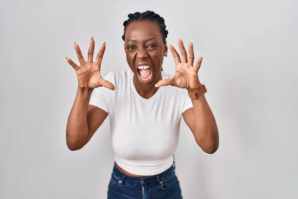 Beautiful black woman standing over isolated background smiling funny doing claw gesture as cat, aggressive and sexy expression