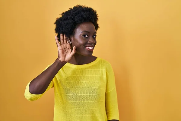 African Young Woman Standing Yellow Studio Smiling Hand Ear Listening — Foto de Stock