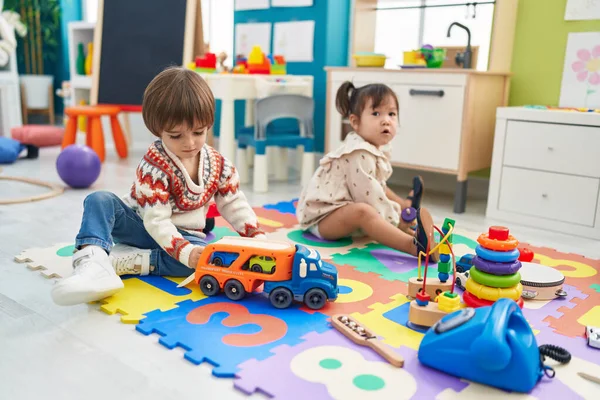 stock image Two kids playing with cars toy sitting on floor at kindergarten