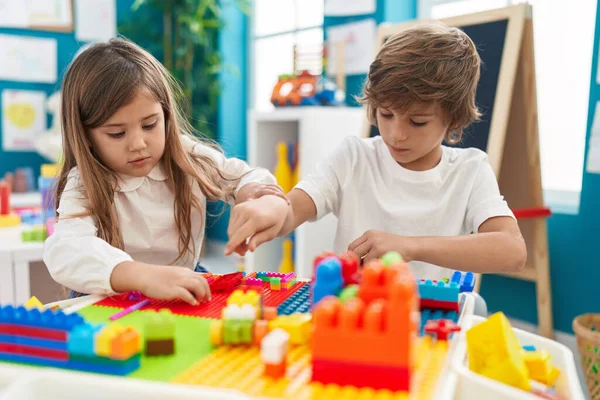 stock image Brother and sister playing with construction blocks sitting on table at kindergarten