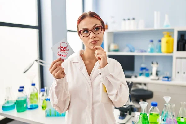 Young Caucasian Woman Working Scientist Laboratory Holding Toxic Label Serious — Stockfoto