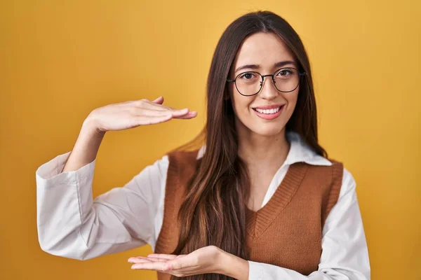 Young Brunette Woman Standing Yellow Background Wearing Glasses Gesturing Hands — Stockfoto