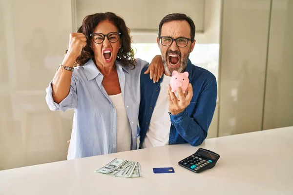 Middle Age Couple Holding Piggy Bank Calculating Savings Annoyed Frustrated — Fotografia de Stock