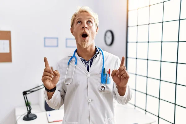 Young Blond Man Wearing Doctor Uniform Stethoscope Clinic Amazed Surprised — Foto Stock