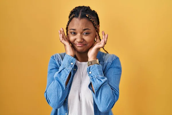 African American Woman Braids Standing Yellow Background Covering Ears Fingers —  Fotos de Stock