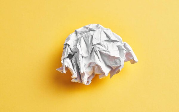  One white crumpled paper ball over isolated yellow background
