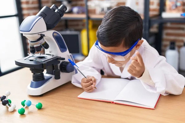 Adorable Hispanic Boy Student Using Microscope Writing Notebook Laboratory Classroom — Photo