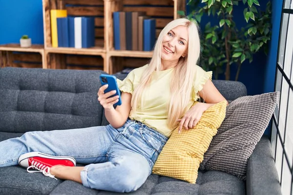 Junge Blonde Frau Sitzt Mit Smartphone Hause Auf Sofa — Stockfoto