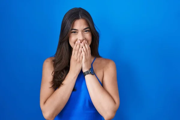 Латиноамериканка Стоящая Синем Фоне Смеялась Смущалась Хихикая Прикрывая Рот Руками — стоковое фото