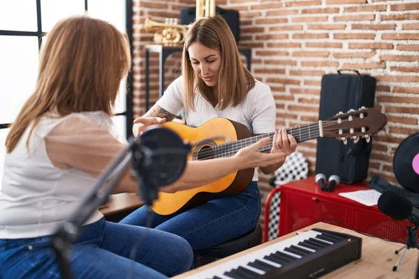 Mother and daughter musicians having spanish guitar class at music studio