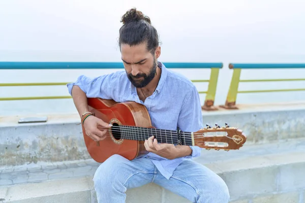 Young Hispanic Man Musician Playing Classical Guitar Sitting Bench Seaside — Zdjęcie stockowe