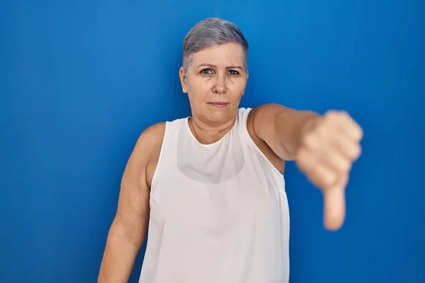 Mavi Arka Planda Duran Orta Yaşlı Beyaz Kadın Mutsuz Kızgın — Stok fotoğraf