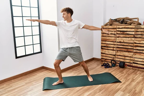 Young caucasian man smiling confident training yoga at sport center
