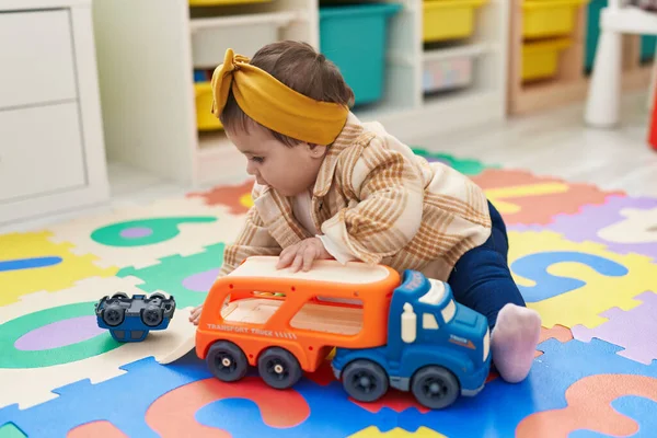 幼稚园里可爱的金发小孩坐在地板上玩卡车 — 图库照片