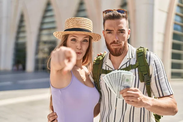 Young Tourist Couple Holding Dollars Banknotes Pointing Finger Camera You — Stock Photo, Image