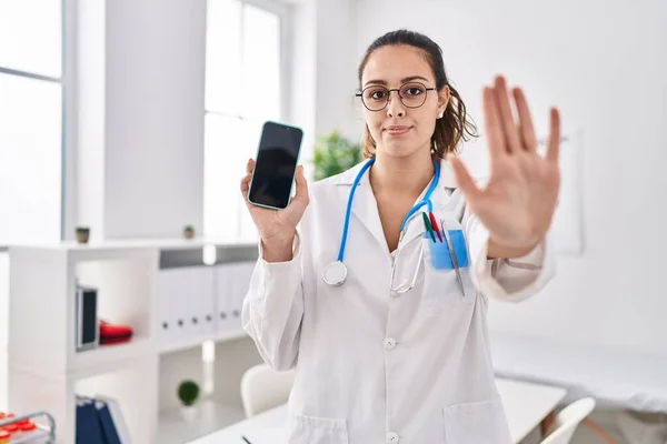 Young Hispanic Doctor Woman Holding Smartphone Showing Screen Open Hand — Stock Photo, Image