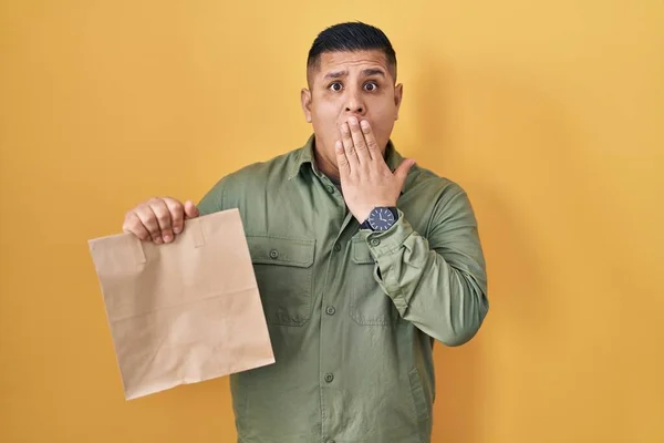 Hispanic Young Man Holding Take Away Paper Bag Covering Mouth — Stock fotografie