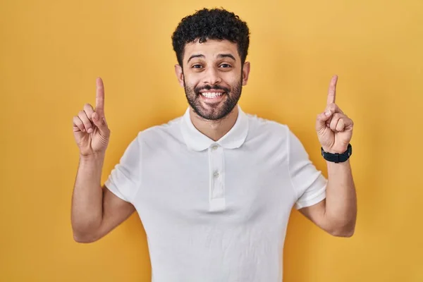 Arab Man Standing Yellow Background Smiling Amazed Surprised Pointing Fingers —  Fotos de Stock