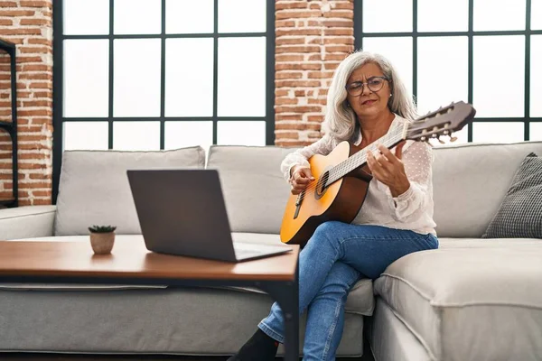 Middle age woman having online guitar class at home
