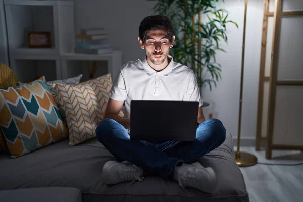 Young Hispanic Man Using Laptop Home Night Looking Camera Blowing — Stok fotoğraf