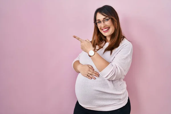 Těhotná Žena Stojící Nad Růžovým Pozadím Veselá Úsměvem Tváři Ukazuje — Stock fotografie