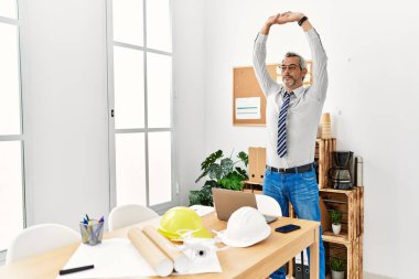 Middle age grey-haired man architect stretching at office