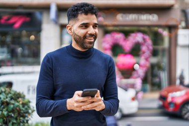 Sokakta akıllı telefon kullanan, kendine güvenen genç bir İspanyol.