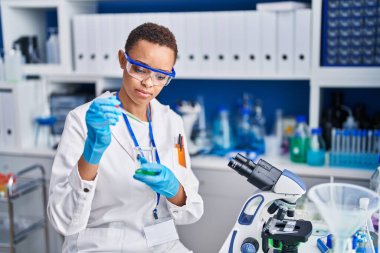 Laboratuvarda test tüpüne sıvı döken Afrikalı Amerikalı kadın bilim adamı.