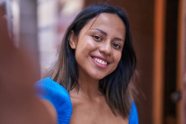 Genç İspanyol kadın gülümsüyor. Kendine güveni tam. Kameranın önünde özçekim yapıyor.