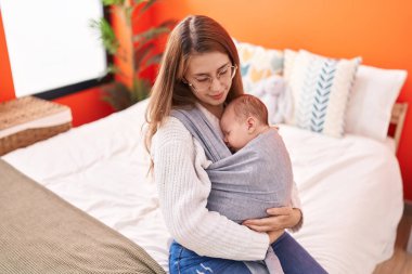 Anne ve oğul yatak odasında birbirlerine sarılıyorlar.