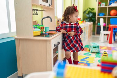 Sevimli sarışın çocuk anaokulunda mutfakta oyun oynuyor.