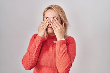 Blonde woman standing over isolated background rubbing eyes for fatigue and headache, sleepy and tired expression. vision problem 