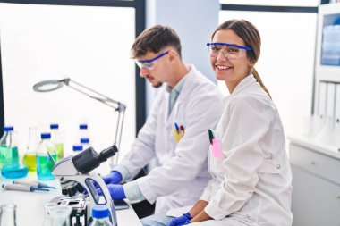 Genç erkek ve kadın bilim adamları laboratuarda çalışan dizüstü bilgisayarlarını kullanıyorlar.